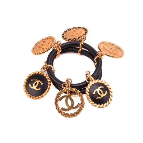 Chanel - two bangles and a necklace; the first is a 1992 padded black  leather bangle, dangling with