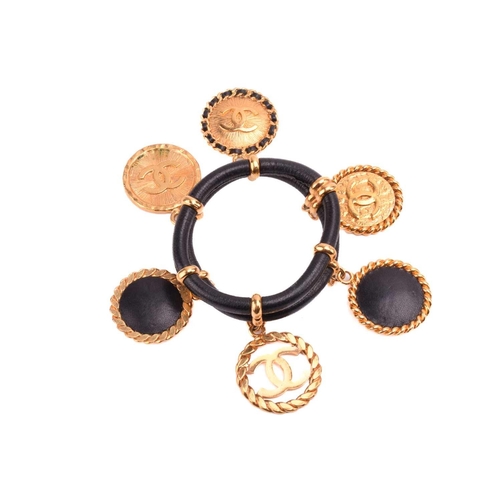 129 - Chanel - two bangles and a necklace; the first is a 1992 padded black leather bangle, dangling with ... 