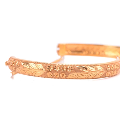 131 - A floral hinged bangle, with engraved foliate decorations and beaded borders, fastens with a push cl... 