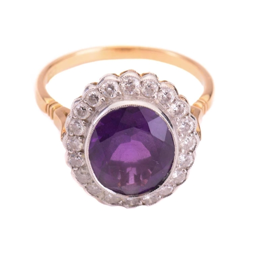 152 - An amethyst and diamond halo ring, featuring an oval-cut amethyst of 11.7 x 9.8 x 5.8 mm, collet-set... 