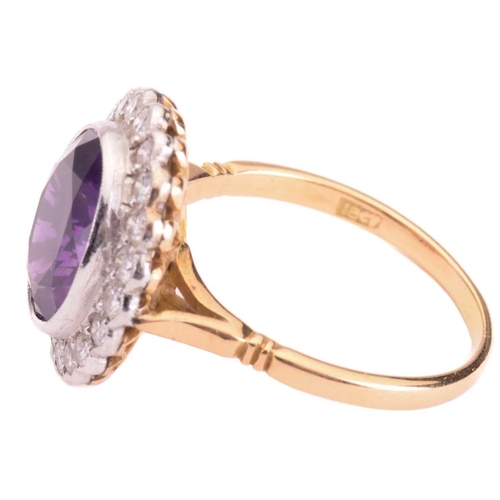 152 - An amethyst and diamond halo ring, featuring an oval-cut amethyst of 11.7 x 9.8 x 5.8 mm, collet-set... 