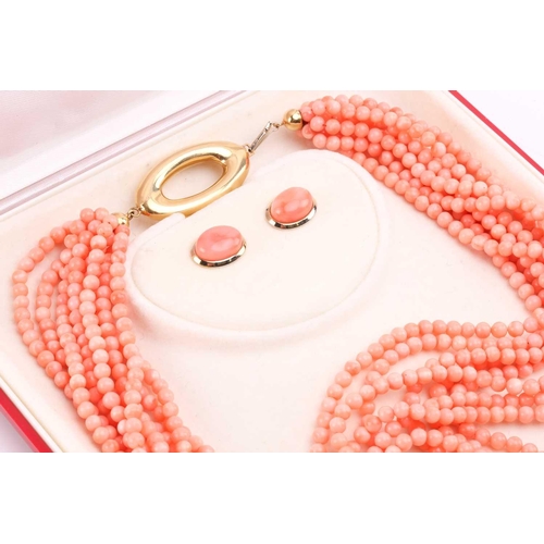 159 - A pink coral torsade necklace and earrings en-suite; the necklace contains nine rows of pink coral b... 