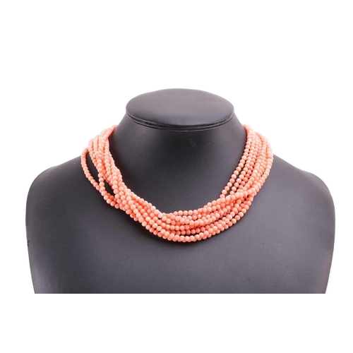 159 - A pink coral torsade necklace and earrings en-suite; the necklace contains nine rows of pink coral b... 