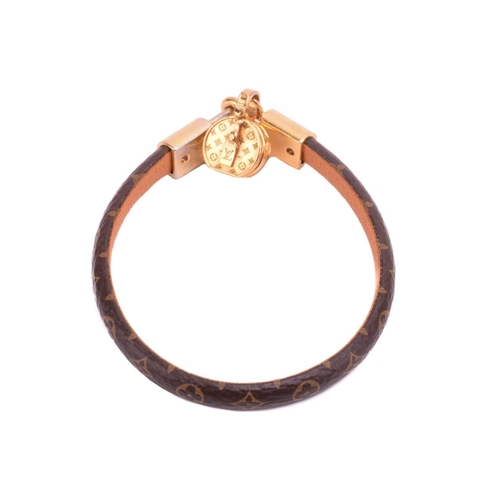 181 - Louis Vuitton - a 'Tribute' bracelet, comprising a monogram canvas strap with leather lining, dangli... 