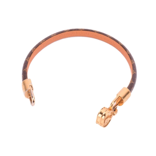 181 - Louis Vuitton - a 'Tribute' bracelet, comprising a monogram canvas strap with leather lining, dangli... 