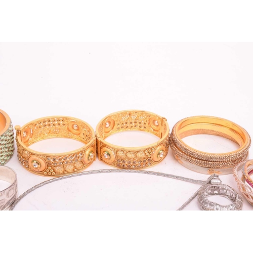 225 - A collection of base metal costume jewellery including Indian style bangles, including hinged exampl... 