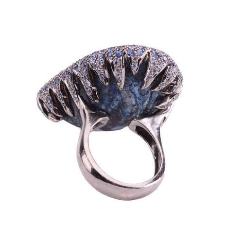 228 - A quartz geode ring of pear form, the black rhodium setting encrusted with round mixed cut sapphires... 