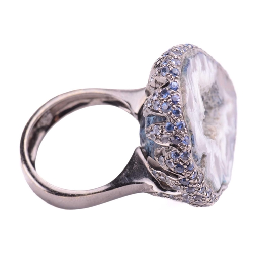 228 - A quartz geode ring of pear form, the black rhodium setting encrusted with round mixed cut sapphires... 