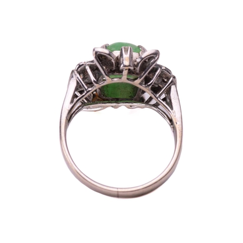 237 - A jade and diamond ring, set with a central sugarloaf cabochon jade measuring 9.4 x 7.5mm, within a ... 