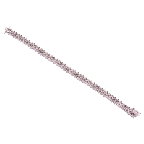 245 - A diamond chevron line bracelet, set with round brilliant cut diamonds in a repeating chevron design... 