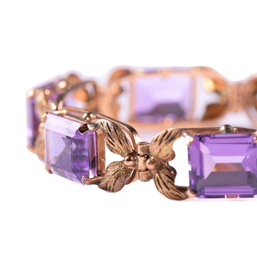 250 - A link bracelet set with seven graduated amethysts, each openwork oblong link claw-set with an emera... 