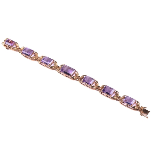 250 - A link bracelet set with seven graduated amethysts, each openwork oblong link claw-set with an emera... 