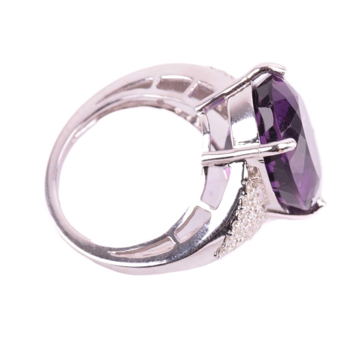 29 - A large amethyst and diamond cocktail ring, featuring an oval-cut amethyst in deep purple colour, ap... 