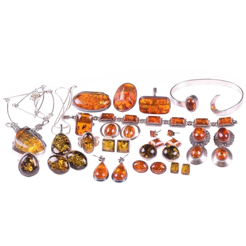 306 - A collection of amber jewellery comprising five rings set in white metal stamped 925, nine pairs of ... 