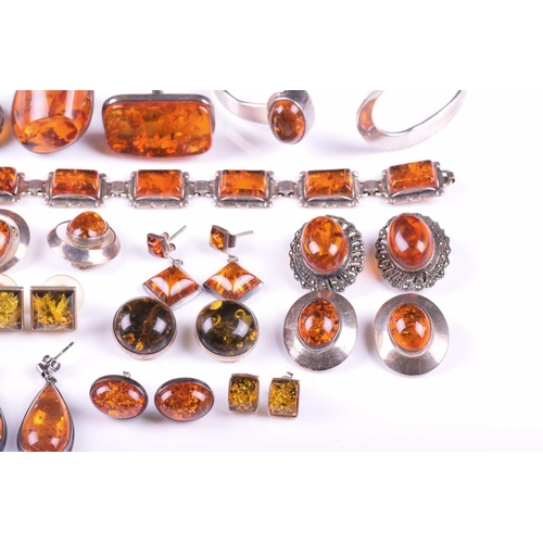 306 - A collection of amber jewellery comprising five rings set in white metal stamped 925, nine pairs of ... 