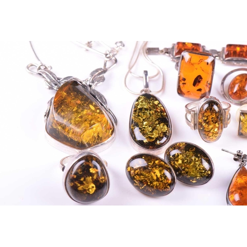 306 - A collection of amber jewellery comprising five rings set in white metal stamped 925, nine pairs of ... 