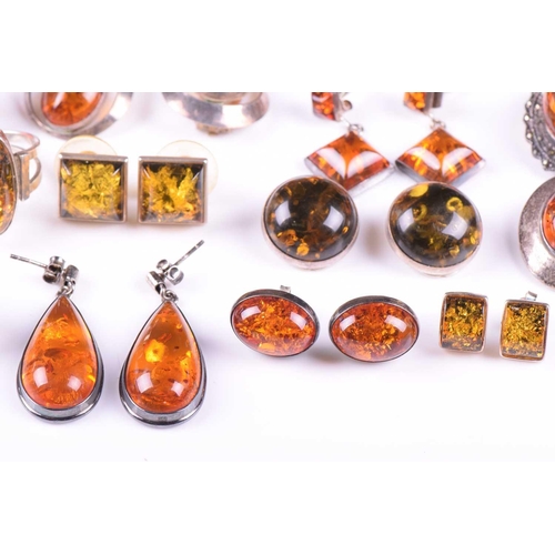 306 - A collection of amber jewellery comprising five rings set in white metal stamped 925, nine pairs of ... 