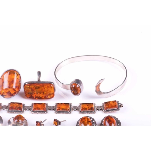 306 - A collection of amber jewellery comprising five rings set in white metal stamped 925, nine pairs of ... 