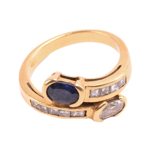 297 - A diamond and sapphire crossover ring, featuring an oval-cut diamond and a sapphire in collet settin... 