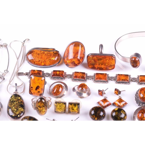 306 - A collection of amber jewellery comprising five rings set in white metal stamped 925, nine pairs of ... 