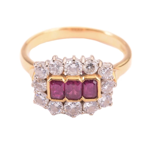 39 - A Ruby and diamond set cluster ring, featuring three central rub set emerald cut rubies surrounded b... 