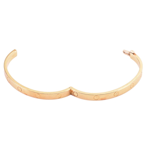 48 - Cartier - a 'LOVE' hinged bangle in 18ct yellow gold, constructed with two arcs engraved with screw ... 