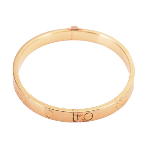 48 - Cartier - a 'LOVE' hinged bangle in 18ct yellow gold, constructed with two arcs engraved with screw ... 