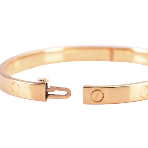 48 - Cartier - a 'LOVE' hinged bangle in 18ct yellow gold, constructed with two arcs engraved with screw ... 