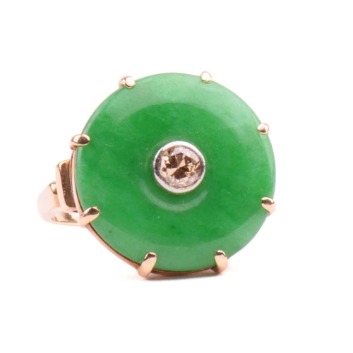 64 - A jade and diamond dress ring; the circular jadeite bi disc of bright green colour, set with a centr... 