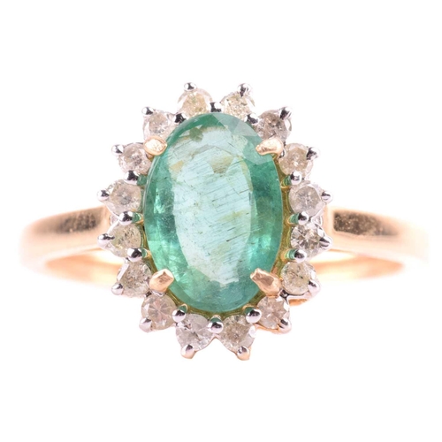 66 - An emerald and diamond halo ring, centred with an oval-cut emerald of pale green colour, approximate... 