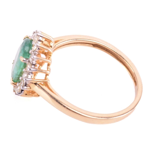 66 - An emerald and diamond halo ring, centred with an oval-cut emerald of pale green colour, approximate... 