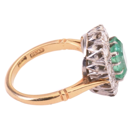 7 - An emerald and diamond cluster ring; the central rectangular step-cut emerald measuring approximatel... 