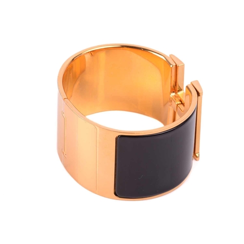 72 - Hermès - an extra wide 'Clic Clac H' bracelet with black enamel and yellow-toned metal, signed and m... 