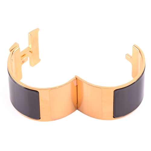 72 - Hermès - an extra wide 'Clic Clac H' bracelet with black enamel and yellow-toned metal, signed and m... 