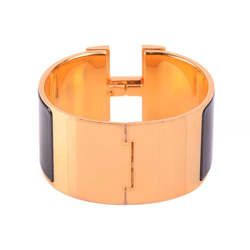 72 - Hermès - an extra wide 'Clic Clac H' bracelet with black enamel and yellow-toned metal, signed and m... 