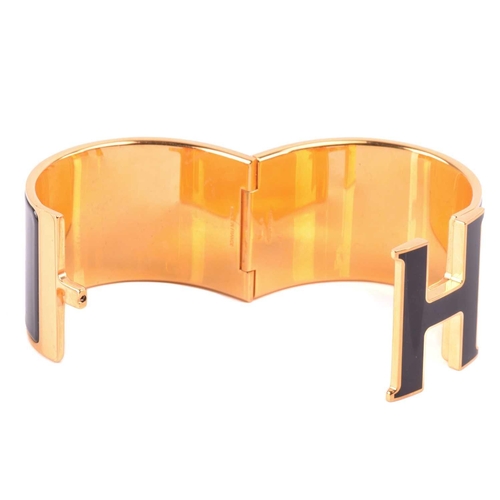 72 - Hermès - an extra wide 'Clic Clac H' bracelet with black enamel and yellow-toned metal, signed and m... 