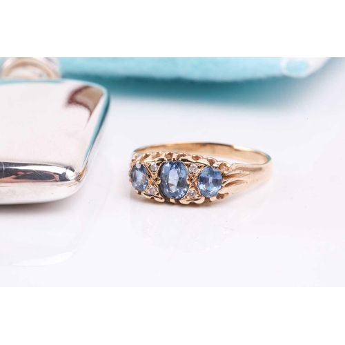 91 - A sapphire and diamond ring, the central oval cut sapphire flanked by two old cut diamonds to either... 