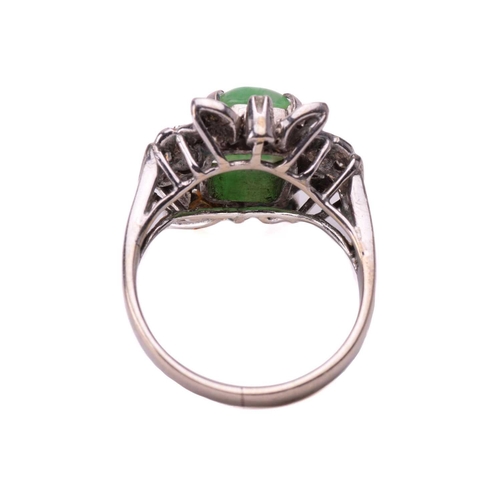102 - A jade and diamond ring, set with a central sugarloaf cabochon jade measuring 9.4 x 7.5mm, within a ... 