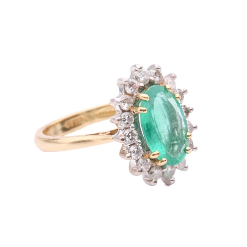107 - An emerald and diamond cluster ring, the oval mixed cut emerald measuring 11.4 x 7.3 x 3.7mm, within... 
