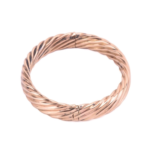 111 - A hinged bangle in twisted rope design, the hollow halves are hinged and fastened together with a co... 