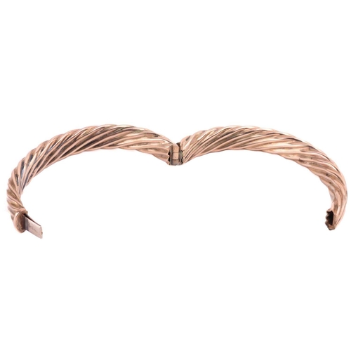 111 - A hinged bangle in twisted rope design, the hollow halves are hinged and fastened together with a co... 