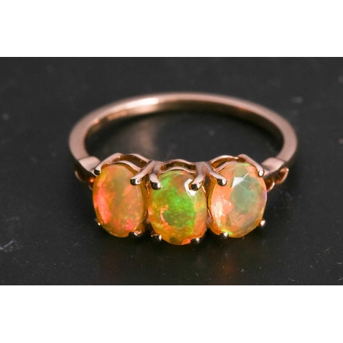 114 - A fire opal trilogy ring in 9ct gold, claw-set with three oval-cut Welo precious fire opals, with st... 