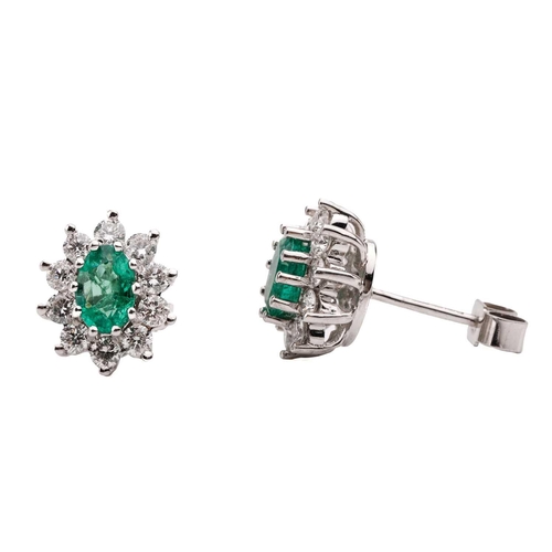 14 - A pair of 18 carat white gold, emerald and diamond earrings; the oval cut emeralds in claw mounts wi... 
