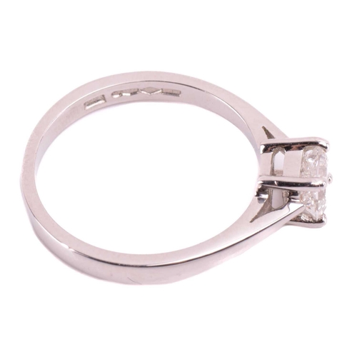 23 - A single stone diamond ring; the princess diamond in four claw mount, to tapered shoulders and plain... 