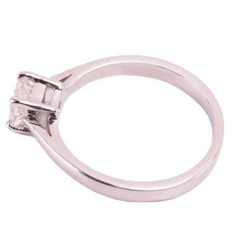 23 - A single stone diamond ring; the princess diamond in four claw mount, to tapered shoulders and plain... 