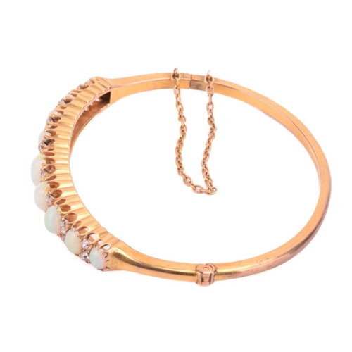 38 - A Victorian opal and diamond hinged bangle, the bracelet features a graduated row of nine oval caboc... 