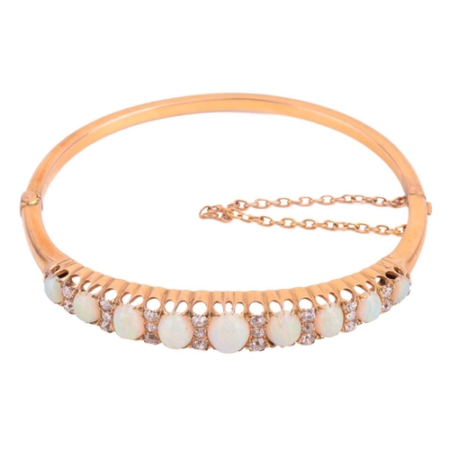 38 - A Victorian opal and diamond hinged bangle, the bracelet features a graduated row of nine oval caboc... 