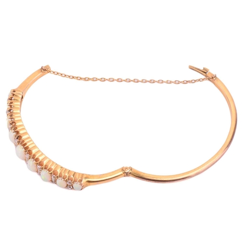 38 - A Victorian opal and diamond hinged bangle, the bracelet features a graduated row of nine oval caboc... 
