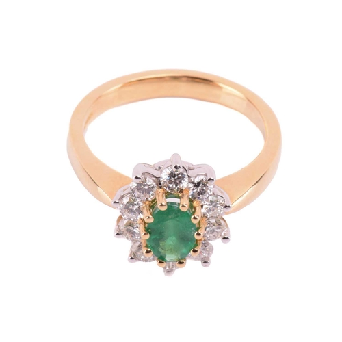 78 - An 18 carat gold, emerald and diamond cluster ring; the oval cut emerald in claw mounts above a bord... 