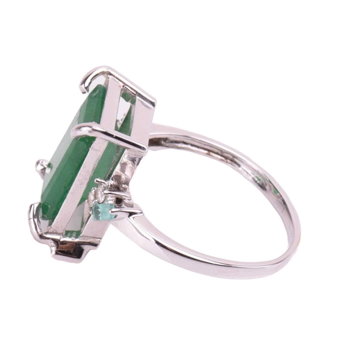 85 - An 18-carat white gold and emerald ring; emerald cut within four claw corner mounts, the shoulders s... 
